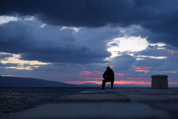 A man is seen fishing during the sunset in Senj