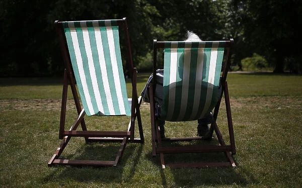A man sits in a deck chair on a sunny day in St. James Park in London, Britain