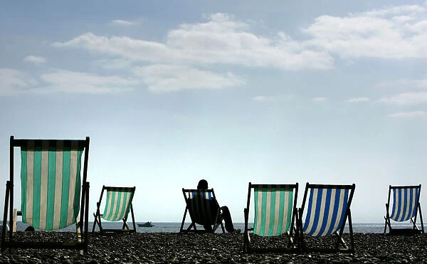A man sits on a deck chair in warm Easter weather on Brighton beach in southern England