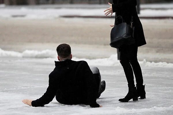 A man slips on icy snow covered sidewalk as freezing rain falls in Toronto