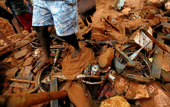 Framed Print : A man stands on top of a damaged bike during a rescue mission at the site of a landslide Framed Print : A man stands on top of a damaged bike during a rescue mission at the site of a landslide