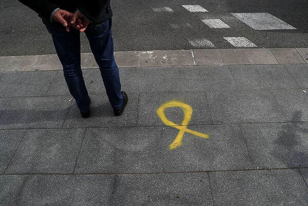 A man stands near a yellow ribbon, the symbol used to demand the release of jailed