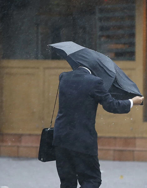 A man struggles against a strong wind and rain caused by approaching Typhoon Wipha at a