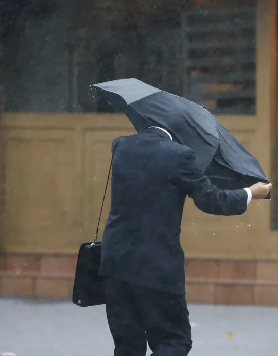 Framed Print : A man struggles against a strong wind and rain caused by approaching Typhoon Wipha at a Framed Print : A man struggles against a strong wind and rain caused by approaching Typhoon Wipha at a