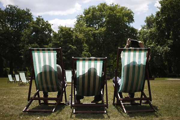 A man takes his jacket off as he settles into his deck chair on a sunny day in St