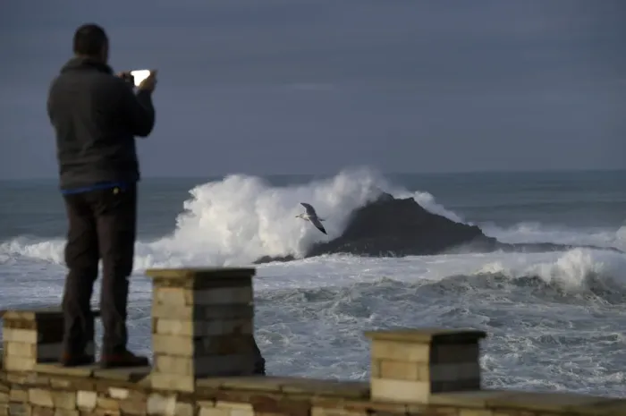 Framed Print : A man takes pictures of waves as they crash against a lighthouse in the port town of Framed Print : A man takes pictures of waves as they crash against a lighthouse in the port town of