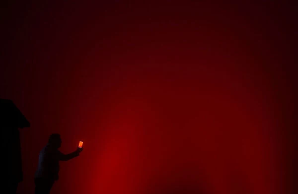 A man tries to take a photo of the Christ the Redeemer statue lit up in red to mark World