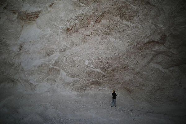A man uses a long stick to hit rocks and get sand in a sand mine on the outskirts of Fond