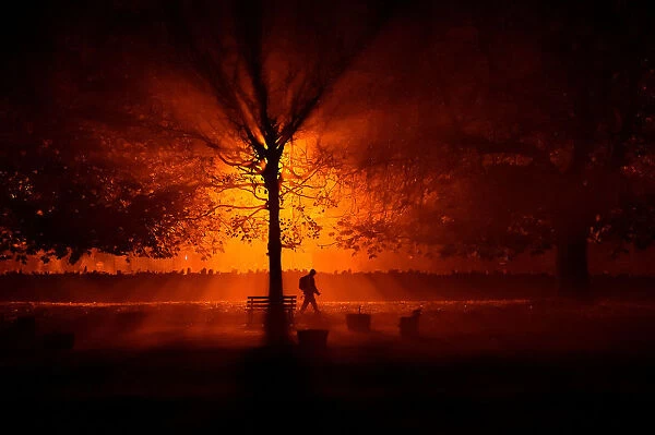 A man uses a torch to walk through a park during cold fog at night in Athboy