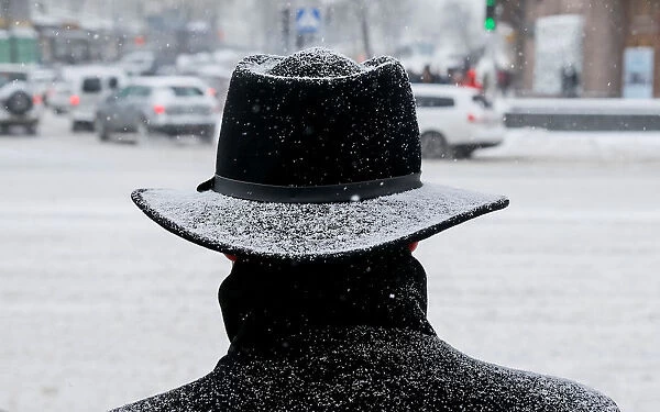A man waits before crossing a street amid a snow flurry in central Kiev