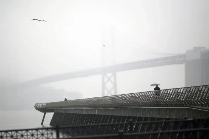 Framed Print : A man walks beneath an umbrella along Pier 14 near the San Francisco Oakland Bay Bridge Framed Print : A man walks beneath an umbrella along Pier 14 near the San Francisco Oakland Bay Bridge