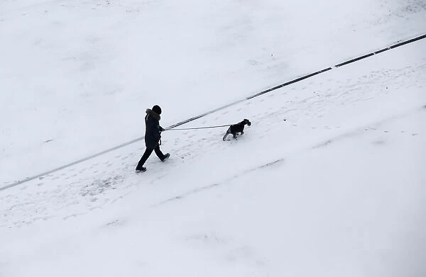 Man walks with a dog after snowfall in Minsk