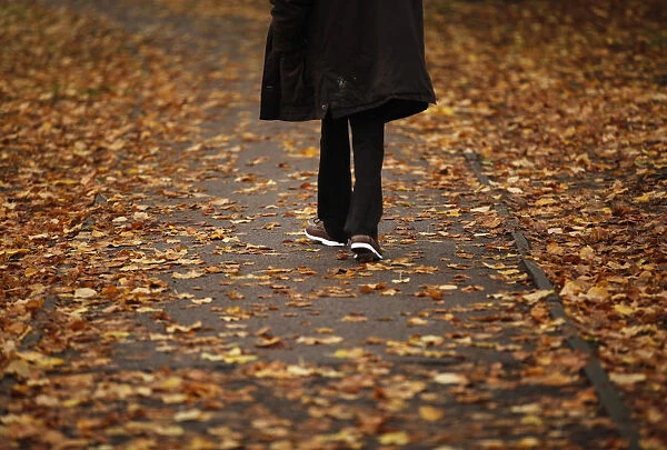 A man walks through fallen autumn leaves in Loughborough