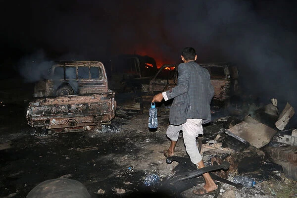 A man walks in front of a fire that broke out at the site of a Saudi-led air strike which