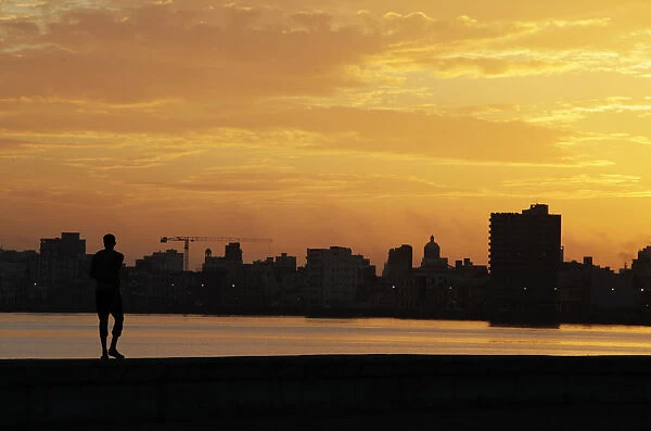 A man walks on Havanas seafront boulevard El Malecon at dawn in Havana