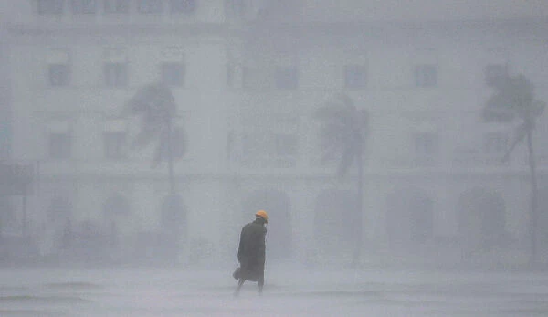 A man walks in heavy rain during a wet day in Colombo
