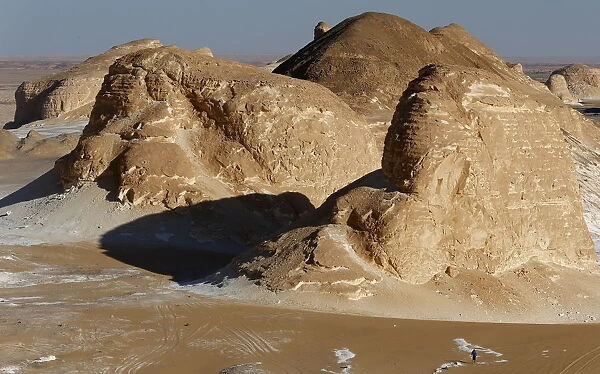 A man walks near rocks which are known as Ajabaat Rocks in the White Desert near