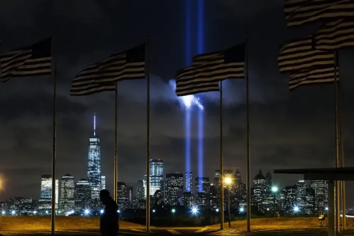 Framed Print : Man walks past as the Tribute in Light is illuminated on the skyline of lower Manhattan