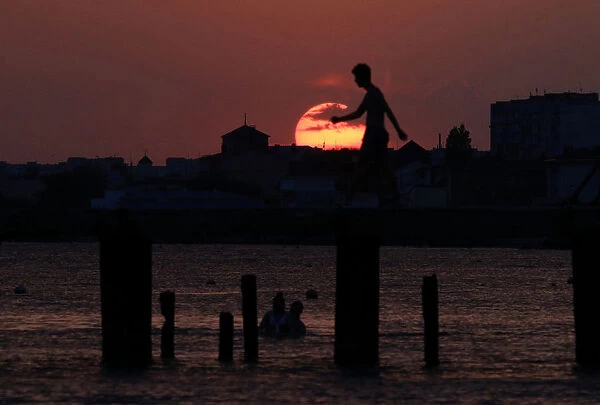 A man walks along a pier during sunset in Yevpatoriya