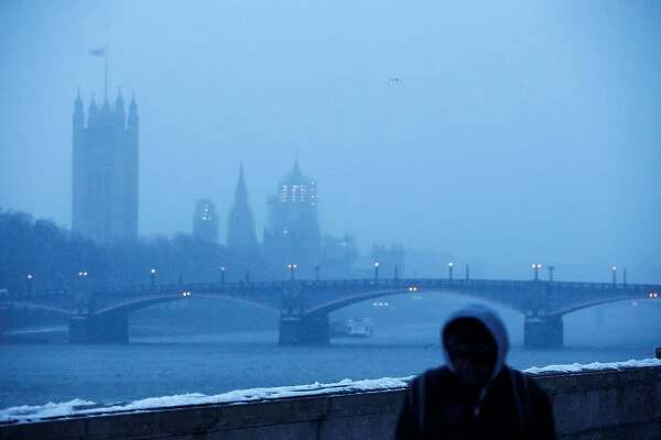 A man walks along the South Bank of the Thames during a snow storm in London