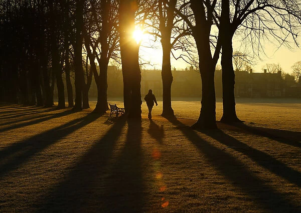 A man walks through Victoria Park at sunrise in Leicester