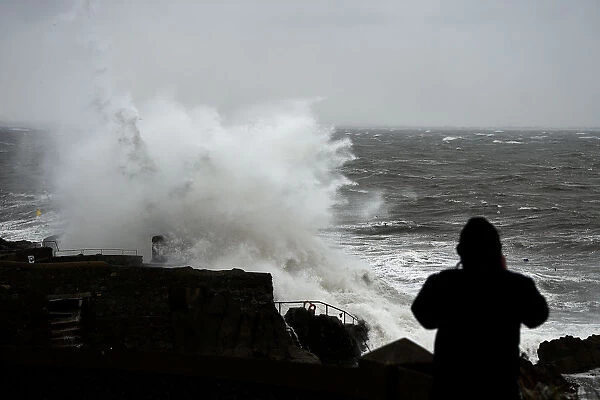 A man watches a large wave break over the Forty Foot diving area as Storm Emma makes