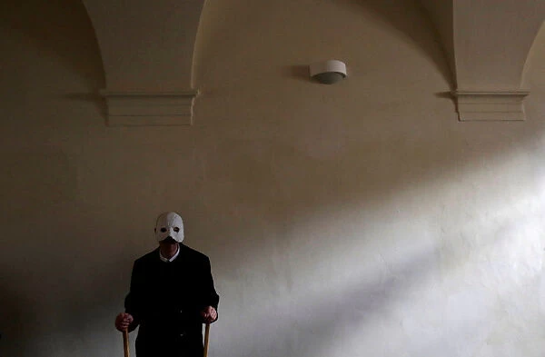 A man wearing a mask prepares to march through the streets during Easter celebrations in