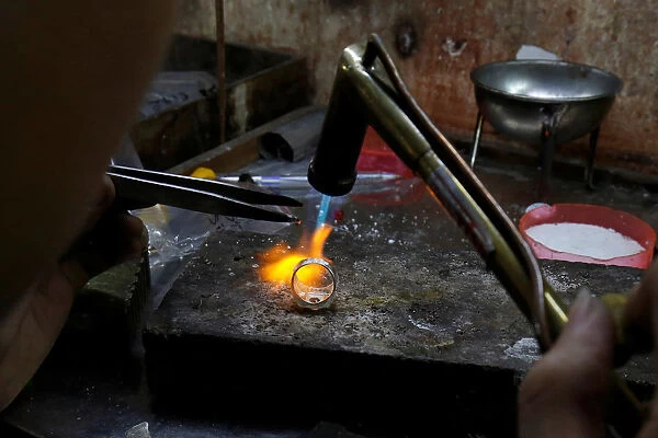 A man works on a silver ring at a workshop in Hanoi