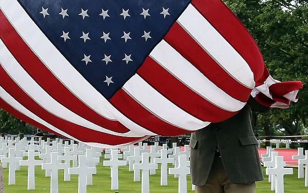 A member of the American War cemetery folds an American flag in Colleville-sur-Me