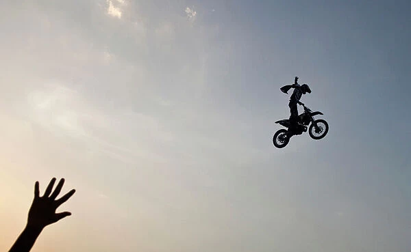 A member of audience waves at a rider performing a stunt during the Red Bull X-Fighters