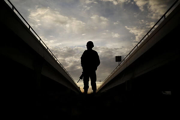 A member of the Mexican National Guard stands near the border fence between Mexico and the U