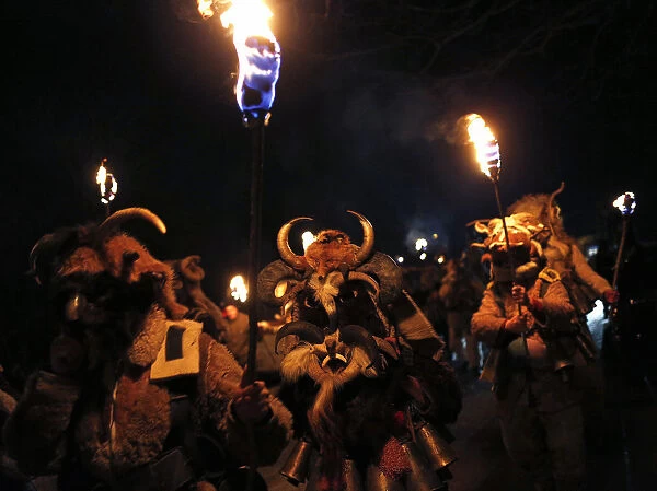 Men dressed in animal costumes, called kuker, carry torches during a festival in the