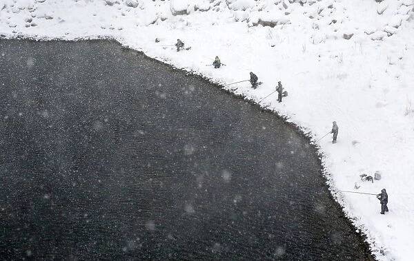 Men fish during snowfall on a bank of the Yenisei River outside Siberian city of Krasnoyarsk