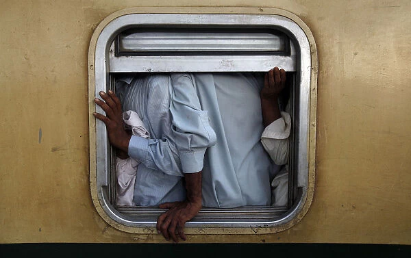 Men are seen at the window of a train as they make their way home, ahead of the Eid