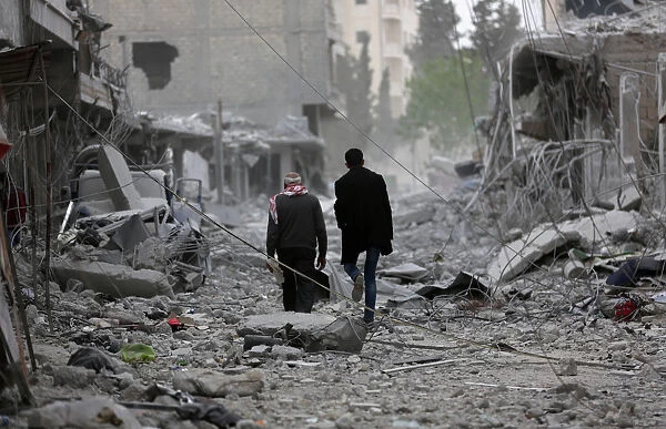 Men walk through debris in the center of Afrin
