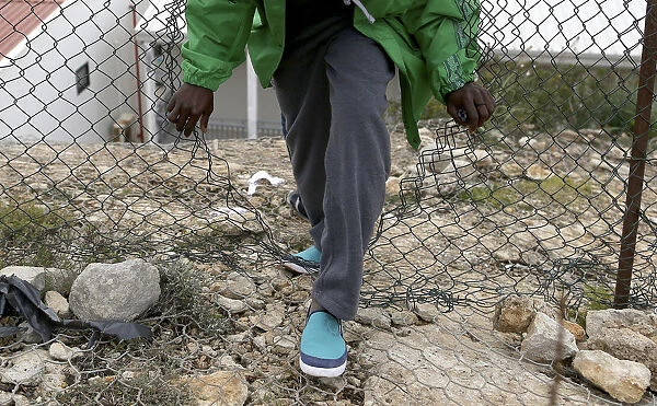 A migrant with her son leaves the immigration centre through a fence on the southern