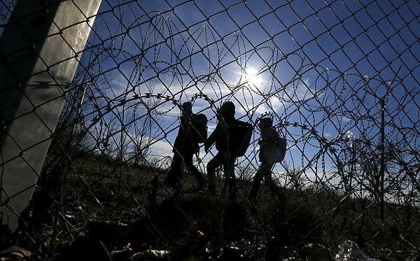 Migrants walk along Hungarys border fence on the Serbian side of the border near