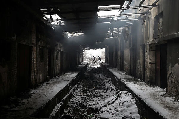 Migrants walk during a snowfall inside a derelict customs warehouse in Belgrade