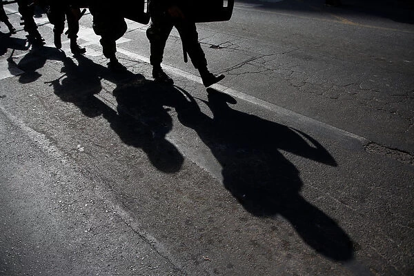 Military policemen cast their shadows as they march toward a protest to mark