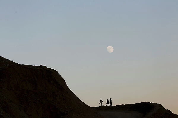 Miners walk along a mountain on their way to search for jade stones at a jade mine in