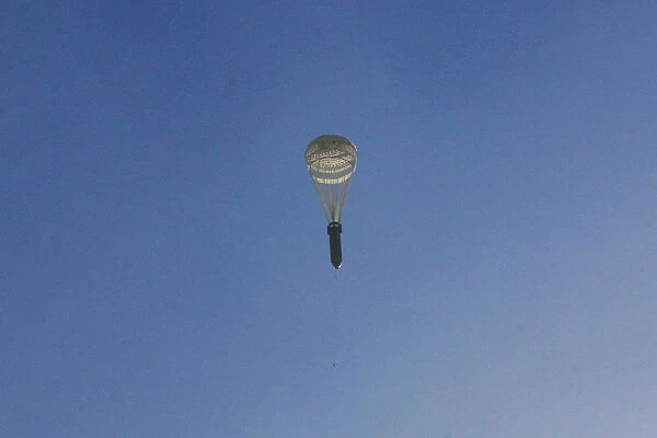 A missile hangs on a parachute while falling over the rebel-held besieged al-Qaterji