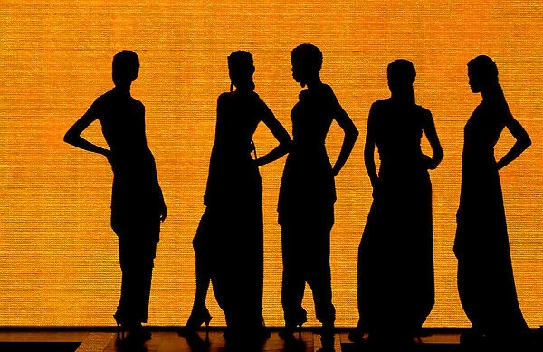 Models are silhouetted as they wear creations at a fashion show