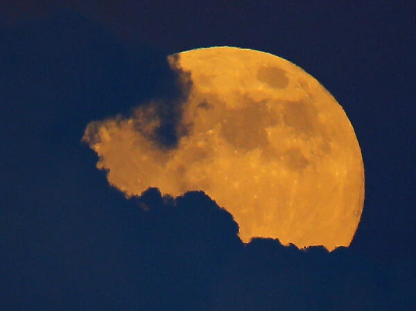 A full moon, also a harvest moon, rises past thunder clouds near Encinitas, California