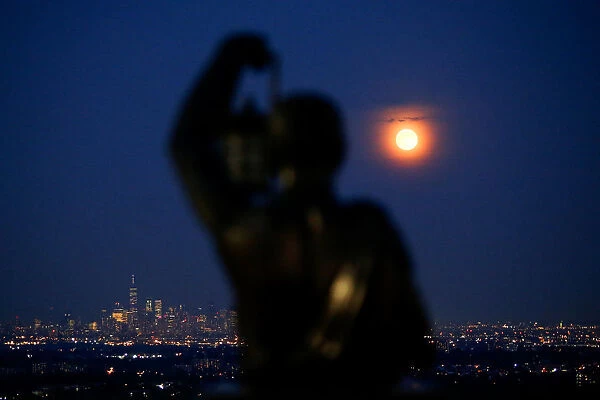 The full moon known rises over the skyline of New York and One World Trade Center as seen