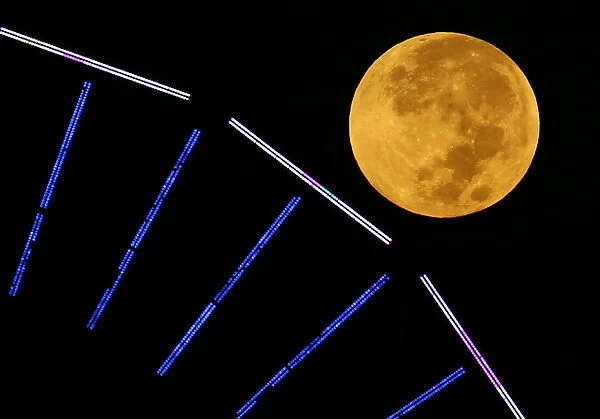The moon is pictured behind a ferris wheel on the pier in Santa Monica, California