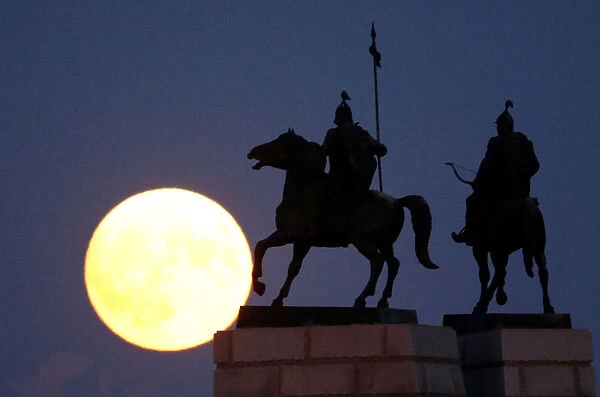 The moon rises behind a monument to Kazakh folk heroes Suranshi and Sauryk in Almaty
