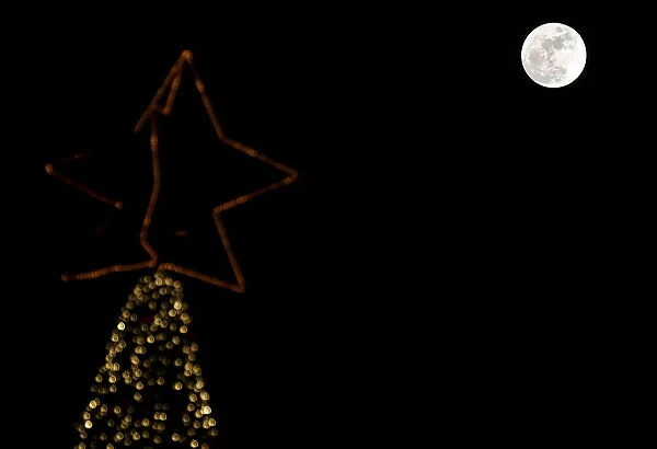 A full moon rises in the sky over a Christmas tree in Beirut, Lebanon