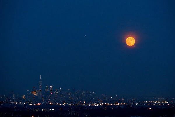 The full moon rises over the skyline of New York and One World Trade Center as seen