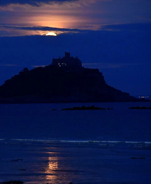 The full moon rises behind St. Michaels Mount in Penzance, Cornwall, Britain