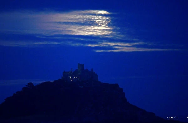 The full moon rises behind St. Michaels Mount in Penzance, Cornwall, Britain